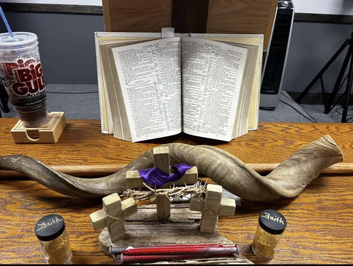 An open Bible with shofars and the communion cup